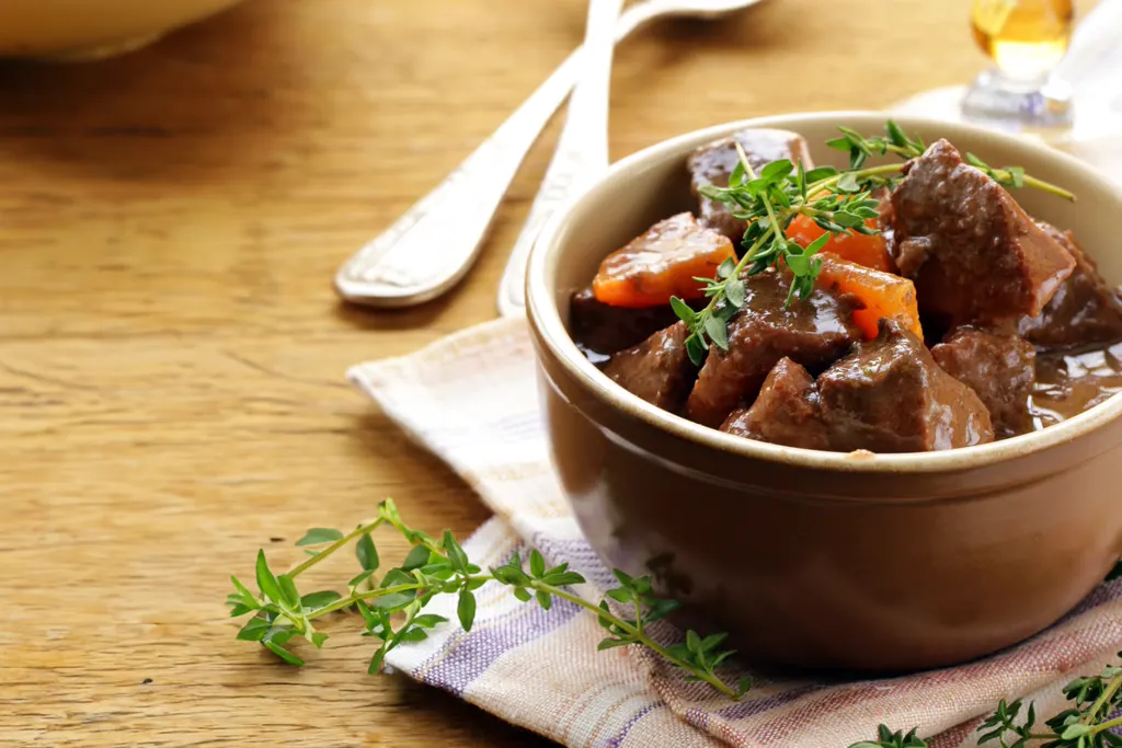 Hot beef bourguignon served in a bowl with fresh thyme
