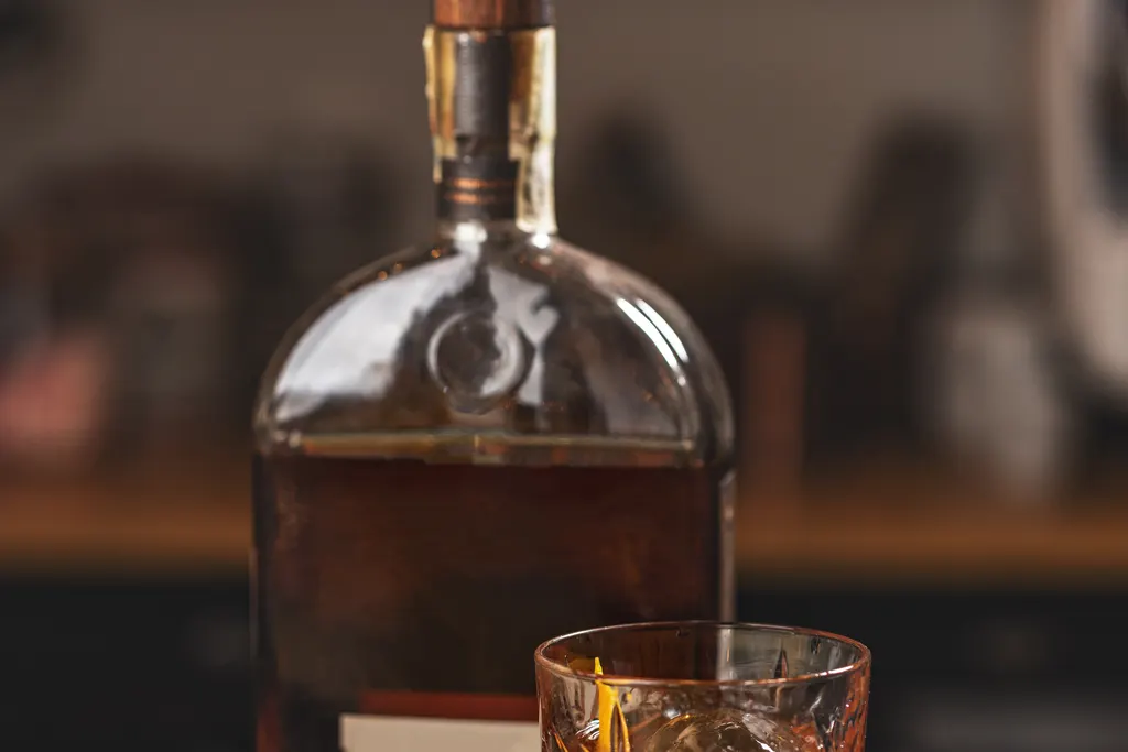 Bourbon bottle and a poured drink on a bar counter