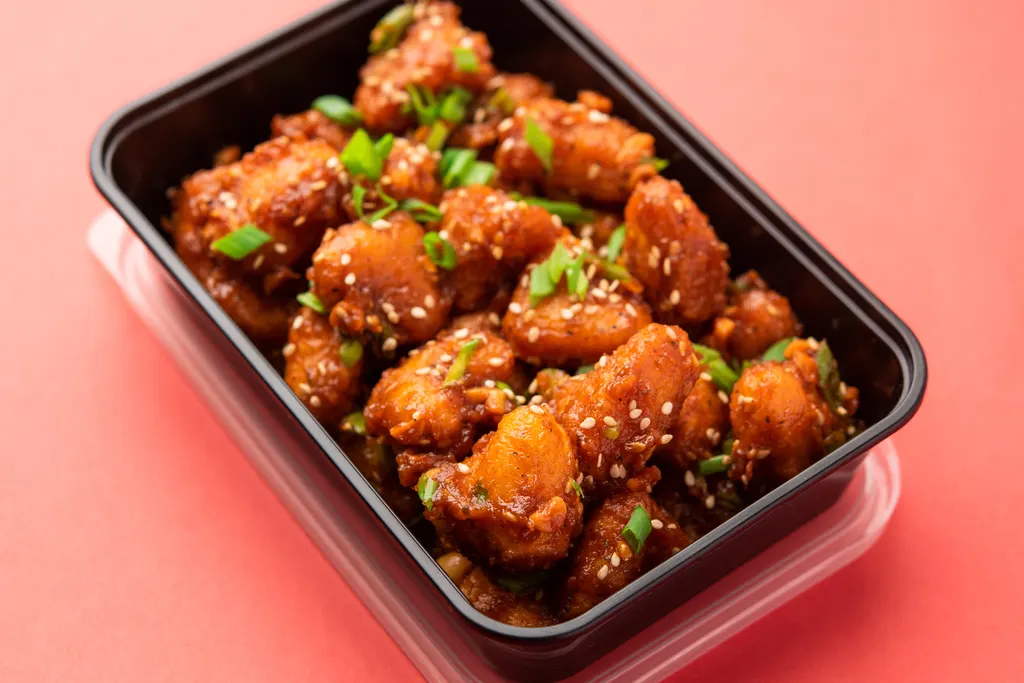 Glazed chicken stored in a black takeout container