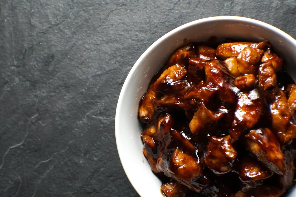 Bowl of chicken pieces in a dark glossy bourbon sauce