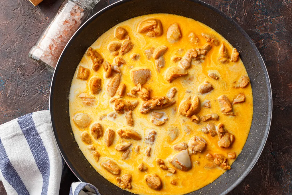 Chicken reheating in a creamy sauce in a pan