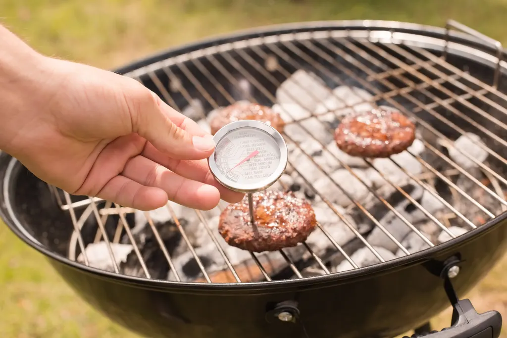 Checking the temperature of hamburgers on the grill with a meat thermometer