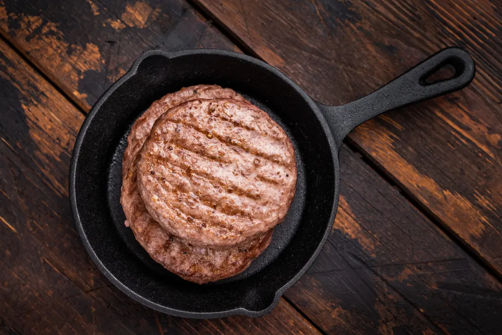 Burger patties reheating in a black skillet