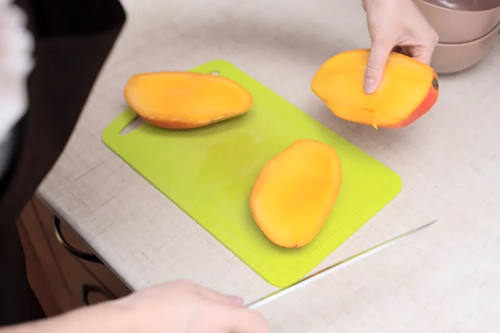 Fresh mango halves on a cutting board